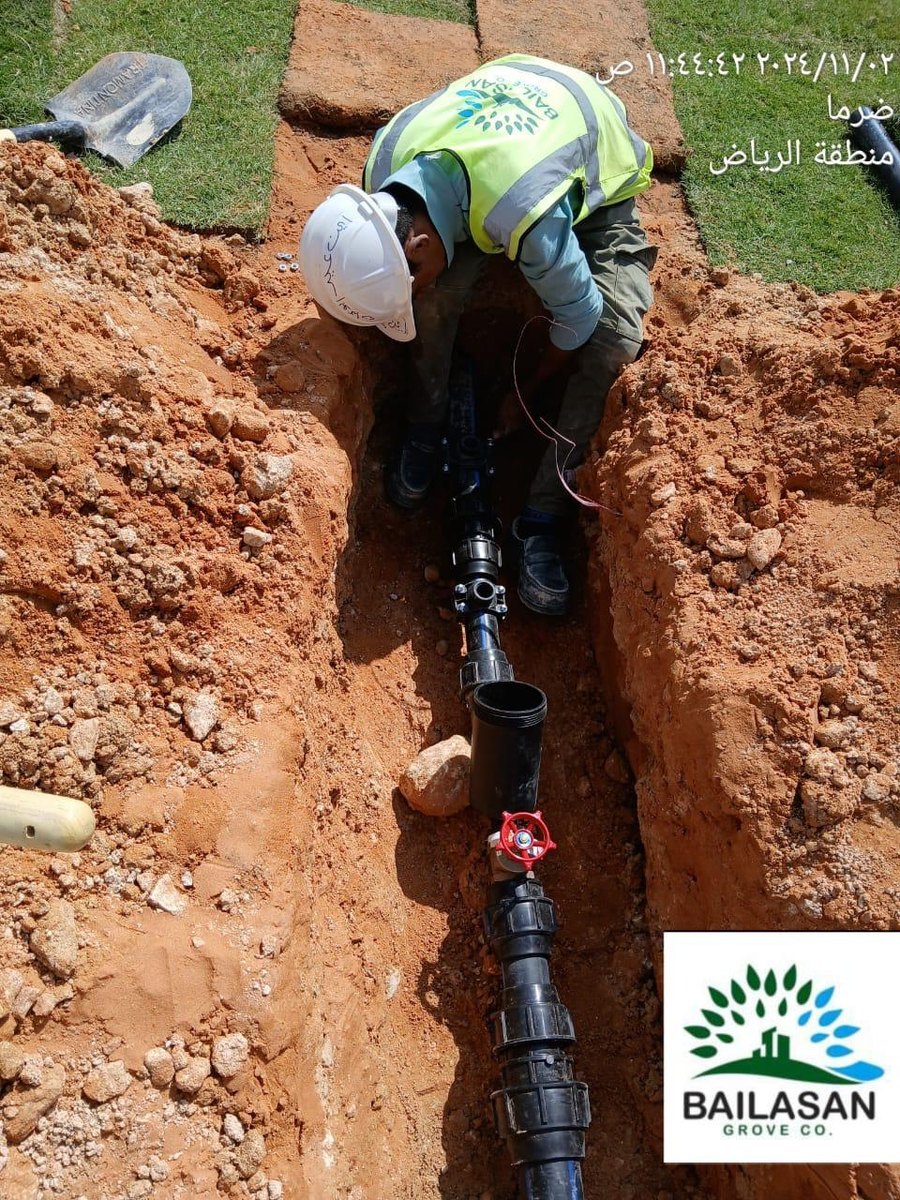 Worker installing irrigation pipe in a trench